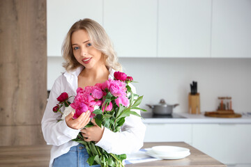 Poster - Young woman with peony flowers in kitchen