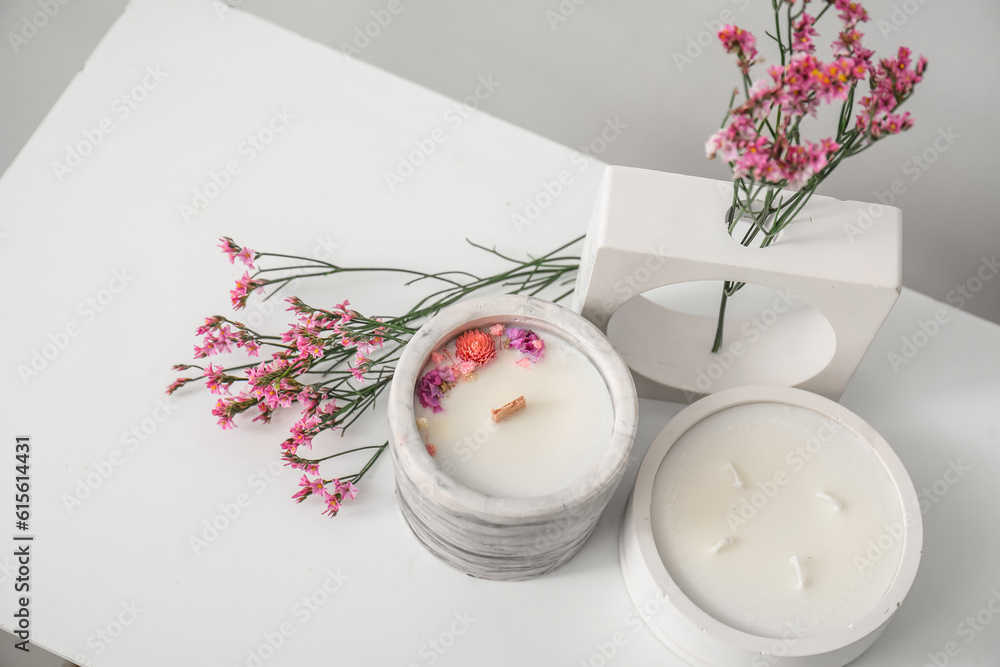 Beautiful flowers and candles on table in room, closeup