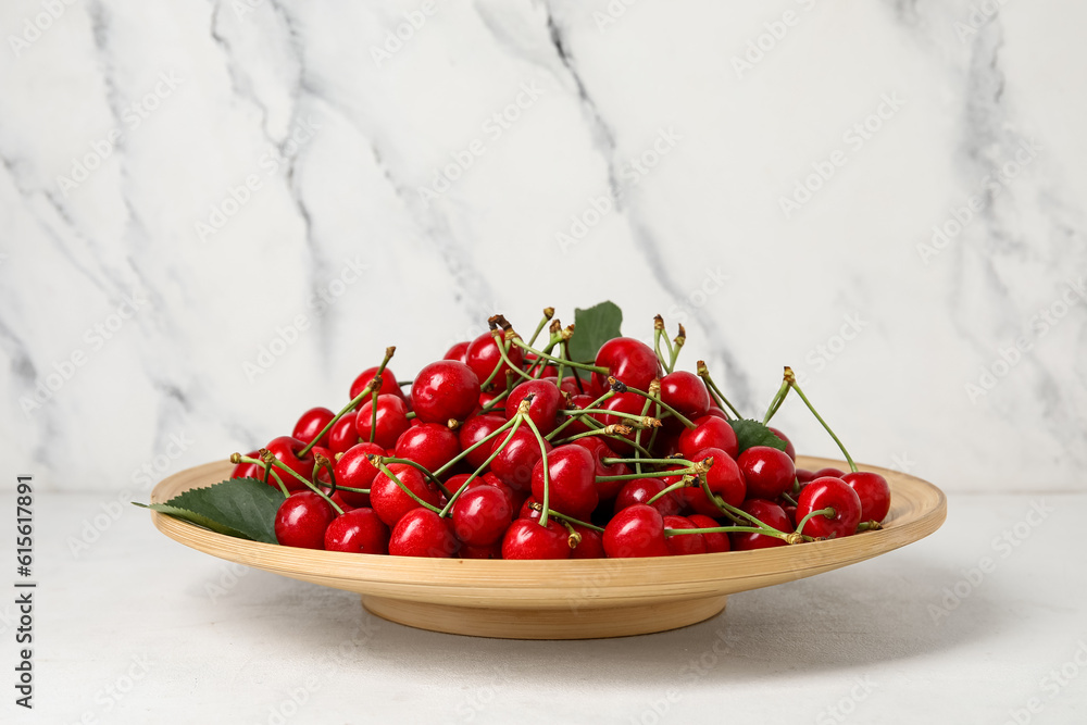 Plate with sweet cherries on white background