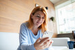 © Baba Images - Mid adult woman using a smart phone at home