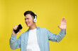 Young man headphones listen to music sing song record voices by cellphones isolated