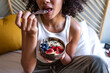 © Daniel - Unrecognizable young multiracial woman eating healthy breakfast bowl of oats and fruit. Breakfast in bed.