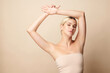 Beautiful Young woman lifting hands up to show off clean and hygienic armpits or underarms on beige background, Smooth armpit cleanliness and protection concept