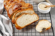 Homemade challah bread with sesame seeds, butter and jam on a grey concrete background. Sweet bread. Selective focus.