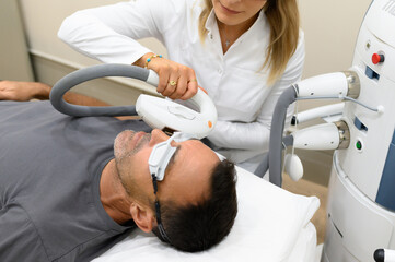 Crop cosmetician applying laser machine on patient