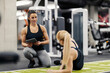 © dusanpetkovic1 - A happy female coach is training sportswoman who is doing side planks in a gym.