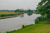 Fototapeta  - Widok na zakole rzeki otoczone zieloną trawą i drzewami