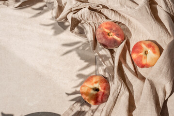 Wall Mural - Aesthetic lifestyle fruit pattern with peaches, crumpled linen fabric and floral sunlight shadow on beige table background