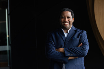 Wall Mural - Portrait of handsome black man wearing suit with arms crossed while smiling