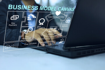 Wall Mural - Businessman planning business a plan with business model canvas through a laptop on the desktop for project presentation and budgeting from high net worth investors value proposition cost and revenue.