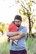 © Austockphoto - Toddler baby hugging father outside in farm paddock