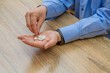 Mężczyzna, pracownik biurowy, trzymający w dłoniach lekarstwa w formie tabletek