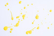 The puddles of an bright yellow oil paint spill. Watercolor yellow drop splash. Splatter of ink drops on white paper background. Sample of cosmetics.