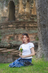 Wall Mural - Pretty Asian tourists woman wearing beautiful hand-woven clothes dyed with indigo and mud-fermented natural colors modern Thai traditional dress costumes are popular in ancient temple Thailand.