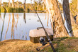 © Austockphoto - A fishing road and tackle box sitting at the base of a gum tree on a river bank