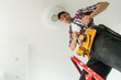 © Angelov - Electrician installer with a tool in his hands, working with cable on the construction site. Repair and handyman concept. House and house reconstruction.
