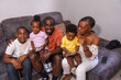 © unai - Portrait of black African ethnicity family with their children on the sofa at home looking at camera