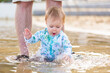 © Austockphoto - Excited baby girl splashing in water at beach on holiday