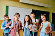 © Drazen - Group of happy school kids in classroom looking at camera.