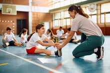 Sports Teacher Assists Her Student In Exercising During PE Class At School.