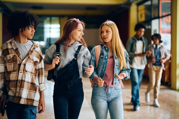 Wall Mural - Female high school students talk while walking through hallway.