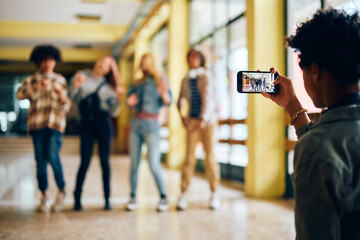 Wall Mural - Close up of high school student taking picture of his classmates with mobile phone.