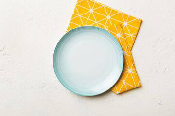 Top view on colored background empty round blue plate on tablecloth for food. Empty dish on napkin with space for your design