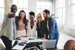 © BullRun - Group of diverse colleagues standing in office with documents and laptop