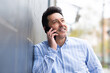 © mimagephotos - Happy older man leaning against wall and making a phone call outside