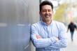 © mimagephotos - Happy mature man standing with arms crossed leaning to a wall
