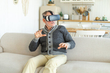 Wall Mural - Excited mature senior man wearing using virtual reality metaverse VR glasses headset at home. Grandfather touching air during VR experience on virtual reality helmet. Simulation hi-tech videogame