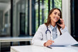 © bnenin - A pretty female doctor having a phone call while doing paperwork at the office.