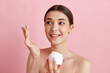 © master1305 - Cream with spf care. Portrait of young beautiful woman posing with face moisturizing cream against pink studio background. Concept of natural female beauty, body and skincare, cosmetology, health, ad