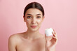 © master1305 - Cream with spf care. Portrait of young beautiful woman posing with face moisturizing cream against pink studio background. Concept of natural female beauty, body and skincare, cosmetology, health, ad
