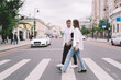 © BullRun - Cheerful couple crossing road on crosswalk during date