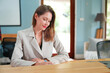 © FotoArtist - Attractive businesswoman in the office, portrait.Smiling female entrepreneur reading paperwork and using a laptop