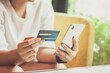 Woman hand using smart phones and holding credit card for shopping payment online, or for business, finance, and payment concepts.