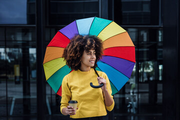 Wall Mural - young African American woman homosexual with rainbow flag or umbrella in city of Latin America, Hispanic and caribbean LGBT female with afro hair