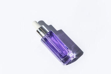 Wall Mural - Purple cosmetic serum bottle with hard shadow on white background. Trendy selfcare products. Top view, flat lay