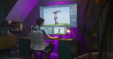 Young 3D designer creates animation for video game character, works remotely from home late night on computer and big digital screen with professional software interface for 3D modeling and design.
