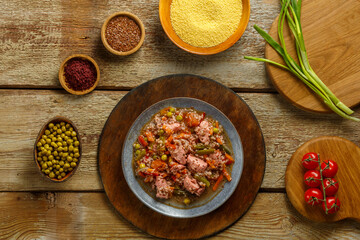 Israeli couscous with sumac and chicken stew pieces on the table in a plate next to the ingredients.