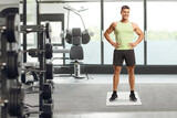 Fototapeta Panele - Fit young man in sportswear smiling at camera and posing at gym