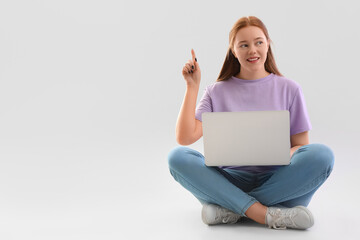 Female programmer with laptop pointing at something on light background