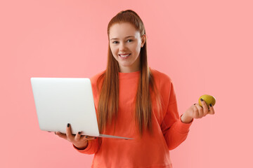Female programmer with laptop and apple on pink background