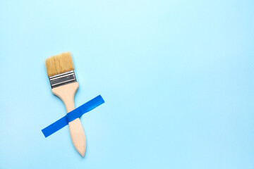 Wall Mural - Paint brush with adhesive tape on blue background