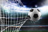 Fototapeta Sport - Ball scores a goal on the net in a football match