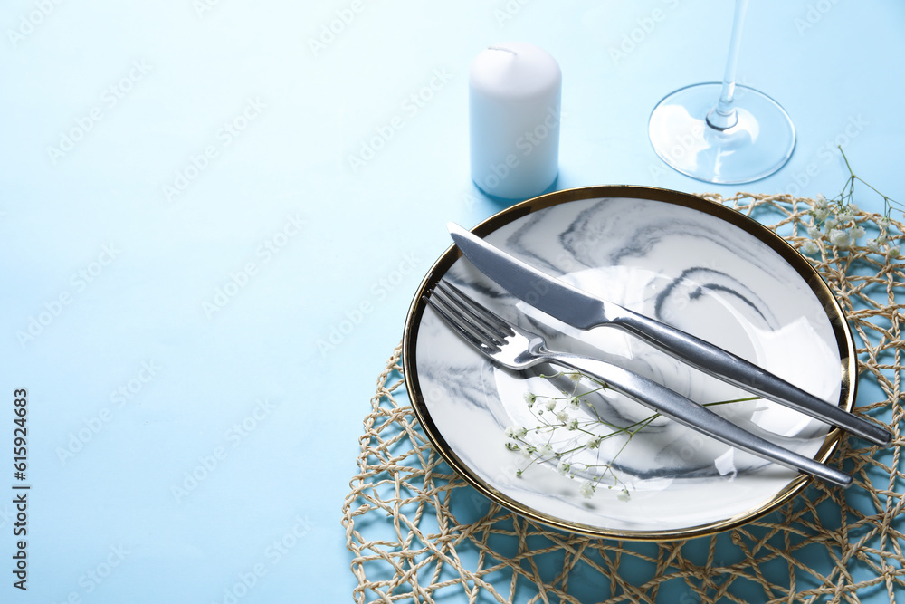 Beautiful table setting with candle and gypsophila flowers on blue background, closeup