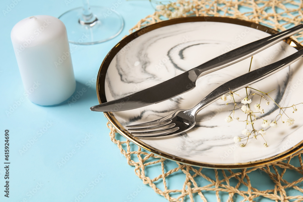 Beautiful table setting with candle and gypsophila flowers on blue background, closeup