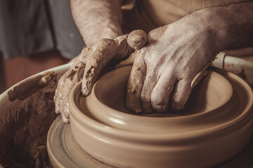 elderly man making pot using pottery wheel in studio.