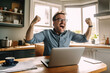 © Djomas - happy man in livingroom with his laptop ai generated